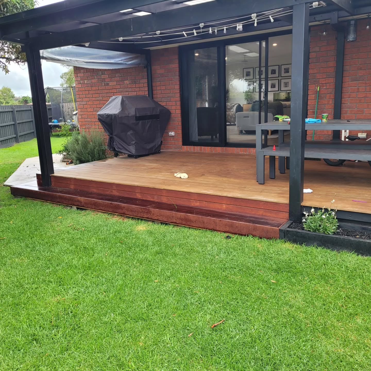 Hardwood deck and black steel pergola built across the back of a brick home