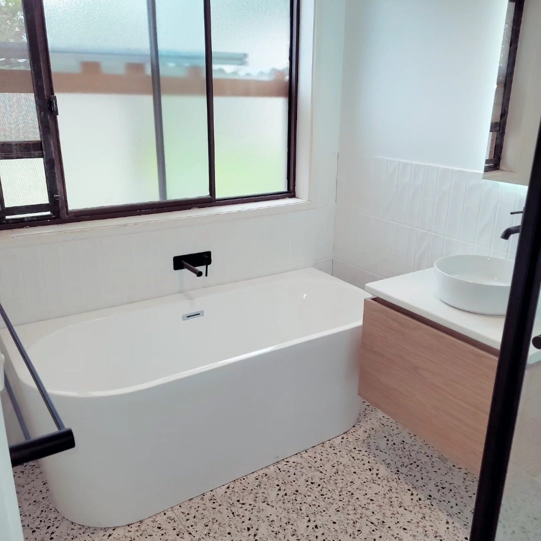Bathroom renovation with a freestanding bath, black tapware and terrazzo floor